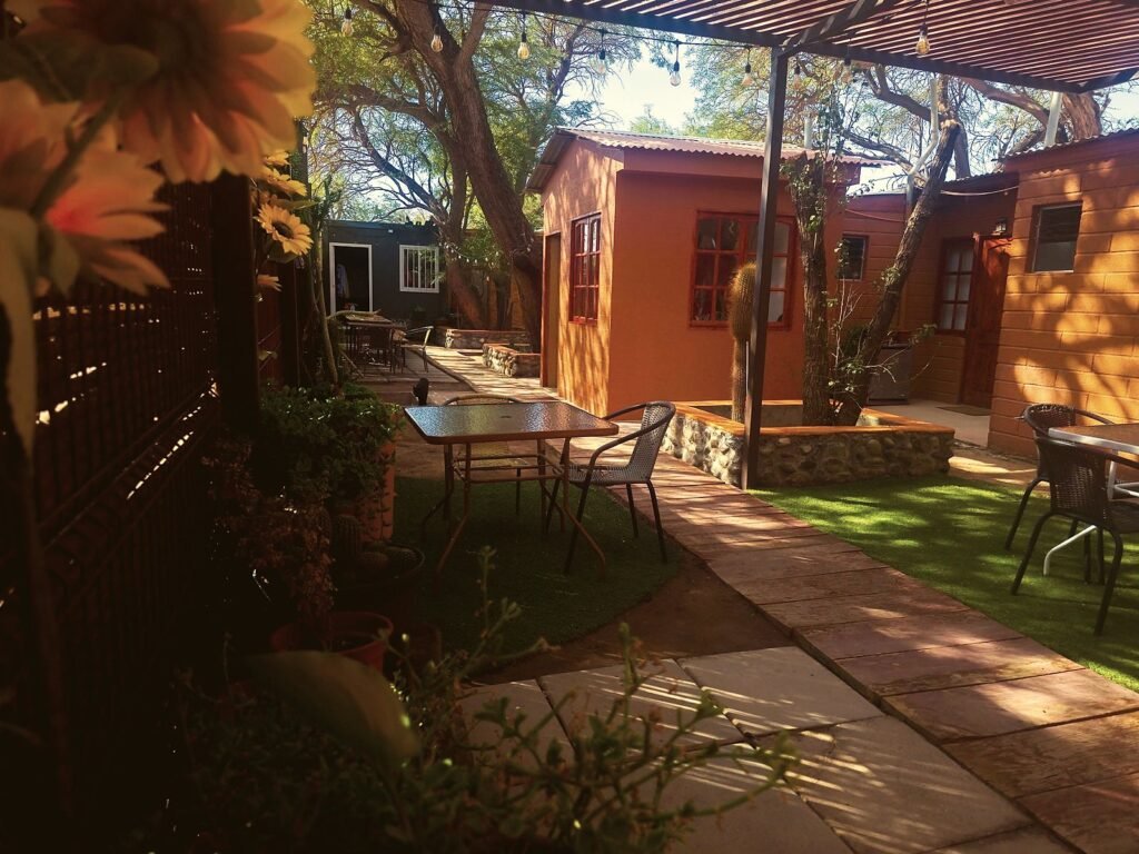 Pasillo del patio con pasto y mesas entre habitaciones