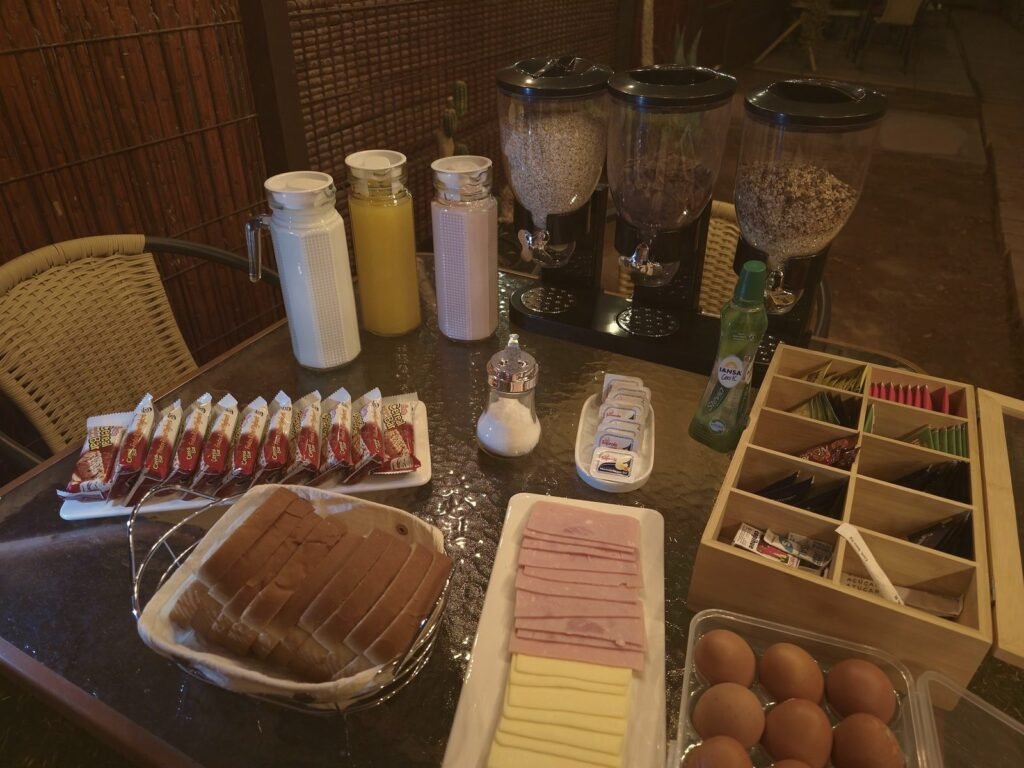 Mesa del desayuno en el patio: cereales, jugos, pan, huevos, té y café
